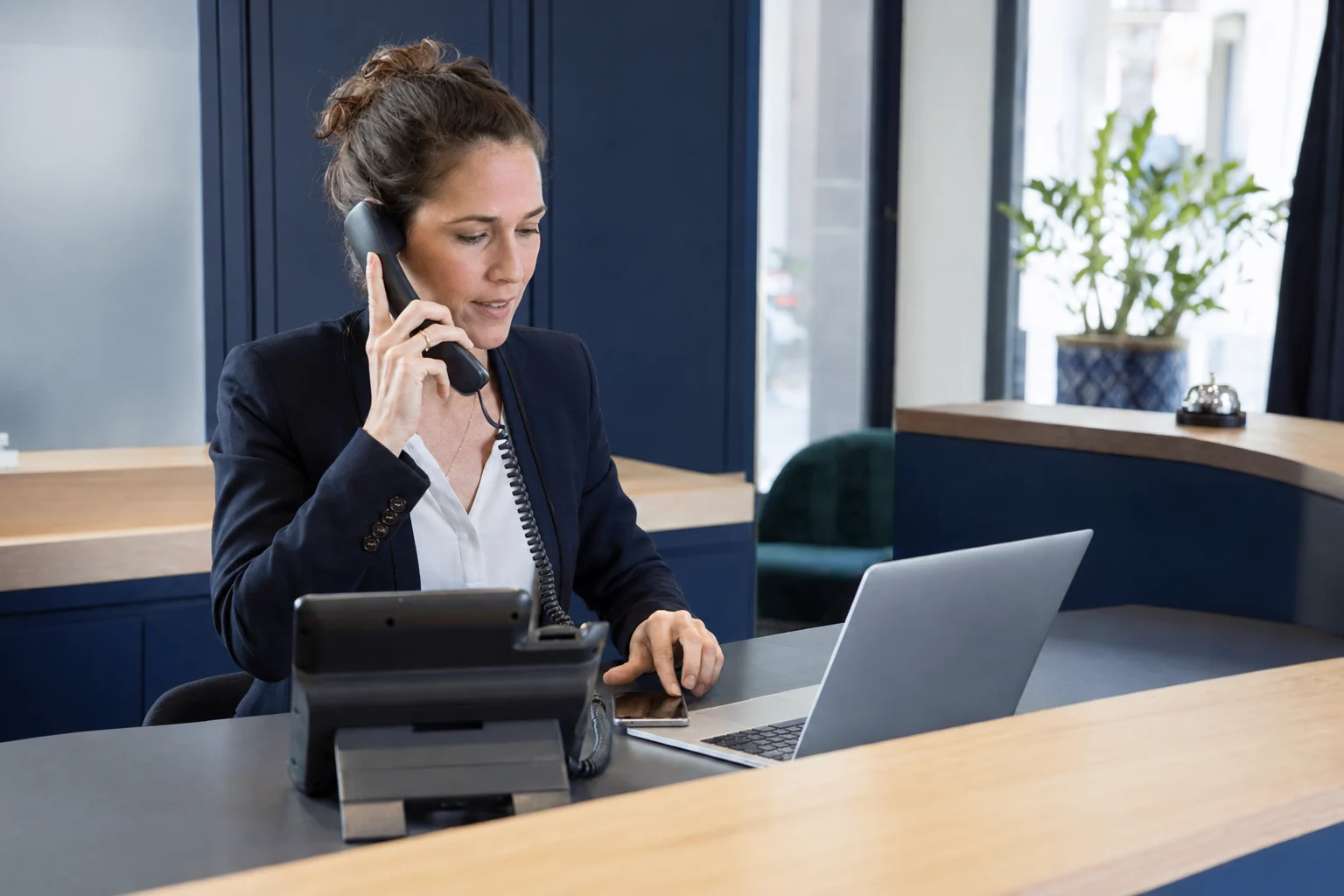 Professionnelle utilisant un téléphone IP, un ordinateur et un mobile